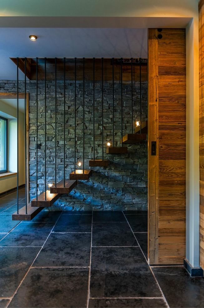 Floating timber staircase against a stone wall